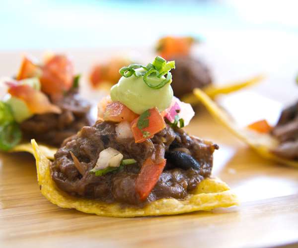Bite size appetizers for events include braised brisket on a house made tortilla chip with pico de Gallo and guacamole